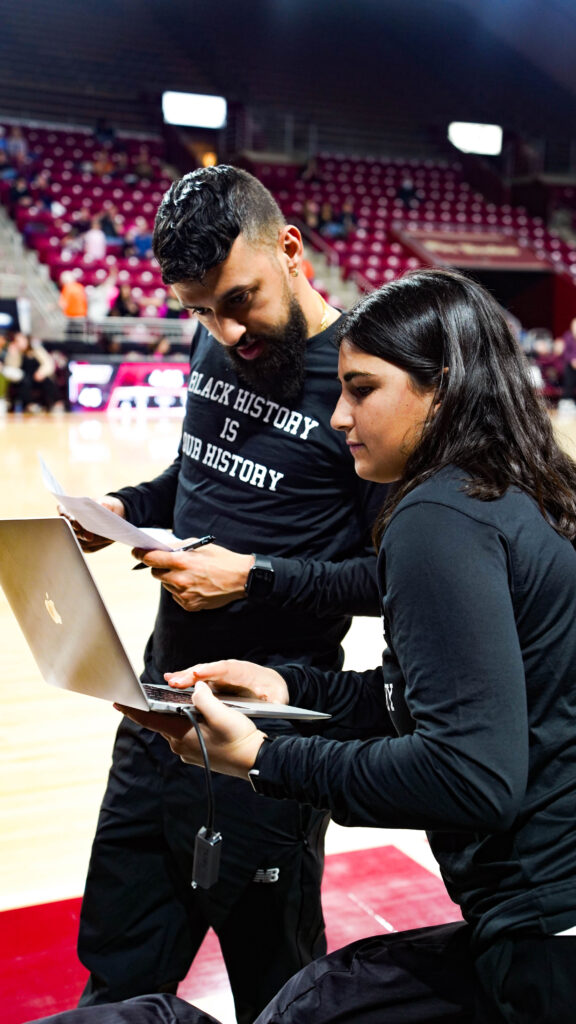 DERRICK SLAYTON, COORDINADOR DE VÍDEO DE BOSTON COLLEGE WBB y su equipo discuten estrategias en la cancha, con un portátil que muestra el software Catapult Pro Video Focus en primer plano. Esta imagen capta la esencia de cómo el flujo de trabajo en directo desde el banquillo facilita los ajustes inmediatos durante el partido y la planificación estratégica.