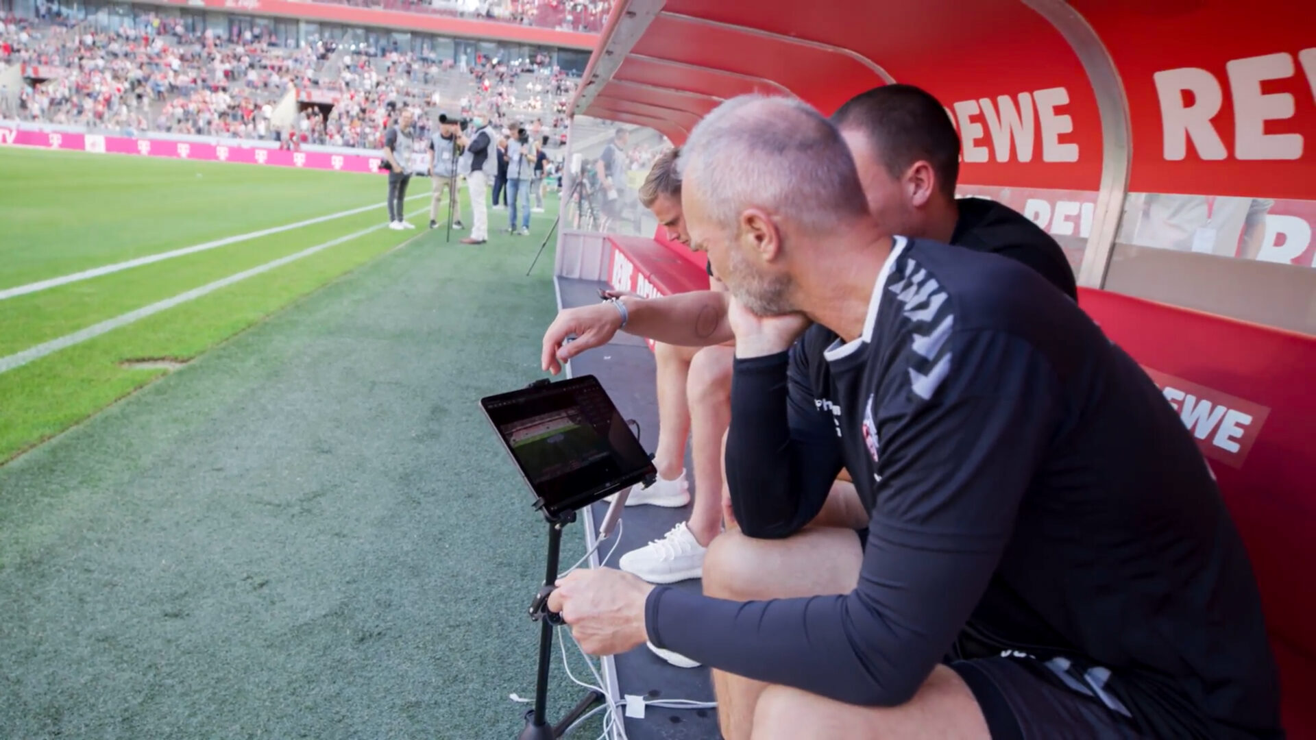 Coaching team using tablets with Catapult Pro Video during a live football match to analyze tactics.