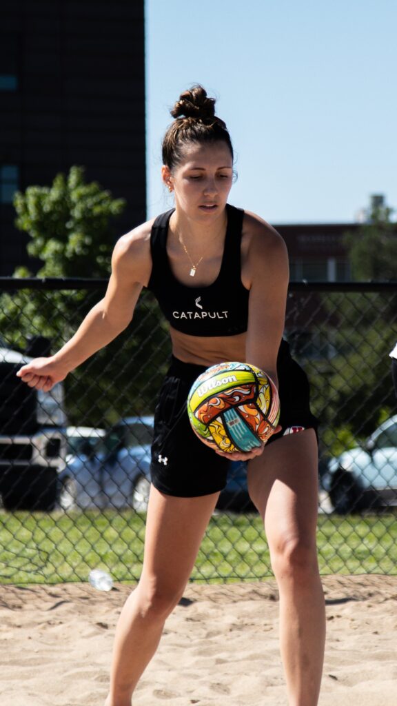Utah Beach Volleyball player wearing Catapult gear prepares to serve during practice.