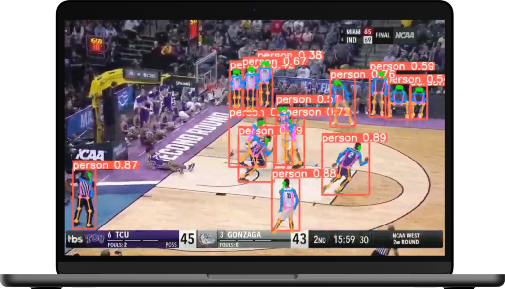 A laptop showing a basketball game with players detected and highlighted by AI, including confidence scores.